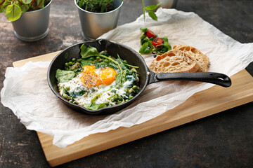 Baked eggs with green peas and spinach. nutritious healthy breakfast. Ready dish served in a hot pan. Suggestion of serving the dish. food background