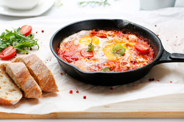 Eggs and tomatoes baked in a pan. Ready dish served in a hot pan. Suggestion of serving the dish.