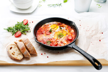 Eggs baked with tomatoes. Ready dish served in a hot pan. Suggestion of serving the dish.