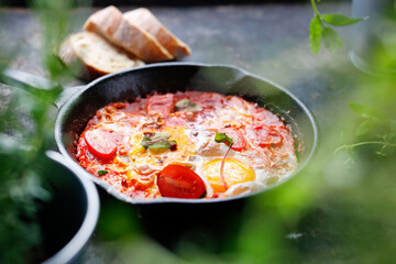 Eggs baked with tomatoes. Ready dish served in a hot pan. Suggestion of serving the dish.