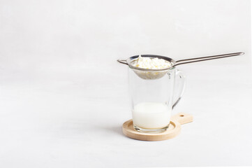 Kefir fermented milk drink with kefir grains. A glass of homemade kefir with kefir grains stands on a white background, horizontal orientation, there is a copy space. Bulgarian drink.