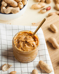 Closeup peanut butter in a glass jar, a handful of peanuts in shell. Foodphoto. Copy space....