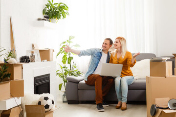 couple moving in together relaxing on sofa couch with laptop computer and boxes