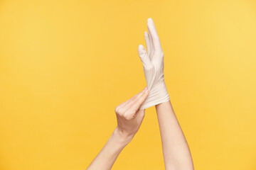 Studio photo of young fair-skinned woman's hands being isolated over orange background while trying...