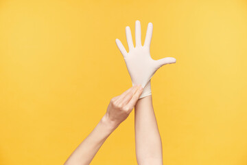 Indoor photo of young female's hand being raised while taking on rubber glove and keeping all...