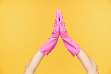 Horizontal photo of raised female's hands in rubber gloves keeping palms together while being...