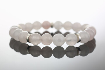 Close up of white bead stretch bracelet jewelry reflecting on glass surface