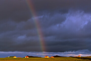 rainbow with heavy rain clouds, and thunderstorm coming on the farm in iceland