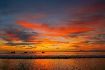Fishermen boats silhouettes in tropical fiery sunset light at Kuta beach, Bali island, Indonesia 