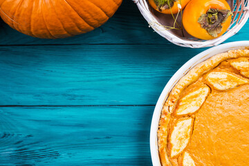 Autumn thanksgiving dark background with pumpkin pie, different pumpkins, fall fruit and flowers on green rustic wooden table.