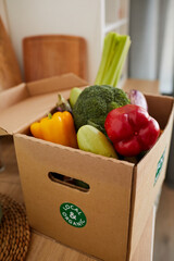 Close-up of cardboard box with fresh vegetables in it on the table being delivered to home