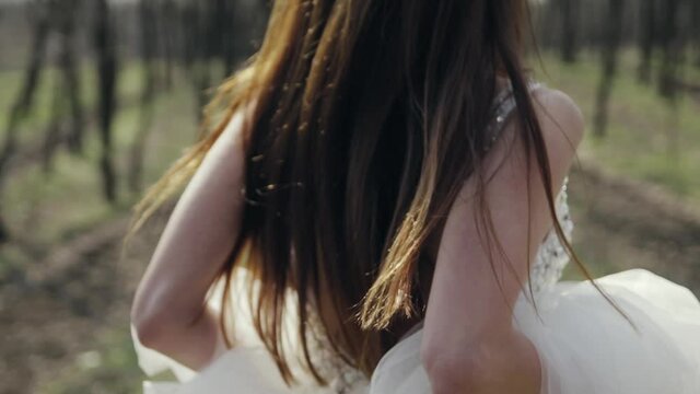 Runaway Bride. Girl with long hair in a white wedding dress runs through the forest in slow motion