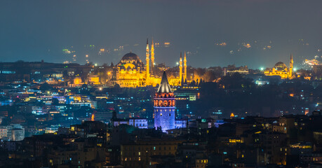 Galata Tower and Suleymaniye Mosque at night in Istanbul, Turkey.