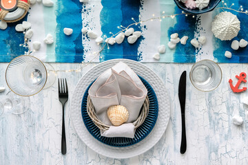 Contemporary summertime table setting with nautical sea decorations on blue and white stripy...