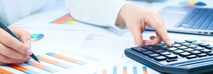 Finance and business concept. Female small business. Hand pointing at statistics chart  calculator on financial graphs on desk. Accounting budgeting loans or tax concept. finance office web banner