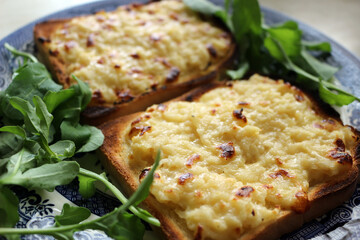Two pieces of cheese on toast served on a plate with salad