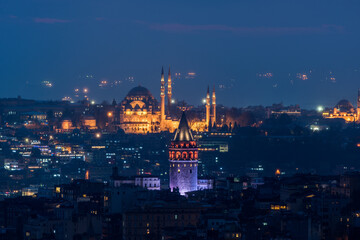 Galata Tower and Suleymaniye Mosque at night in Istanbul, Turkey.