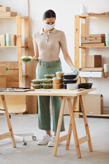 Young woman in protective mask working in food delivery service she packing the food in boxes