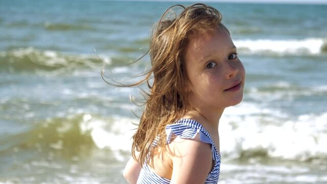 Little kid girl plays on Baltic sea beash shallow waterline summer rest during vacations
