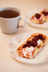 Homemade cheesecakes made from cottage cheese with sour cream and rasberry jam. A cup of tea in the background