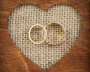 Golden wedding rings background. Vintage heart shape wooden box. Love symbol wedding day.