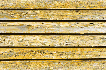 Old peeling paint texture. Grunge cracked wooden wall background. Yellow color weathered surface. Broken wood desk structure. Vintage board pattern design.