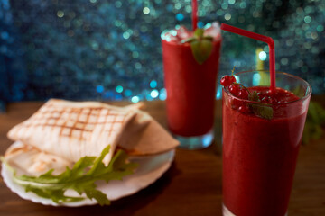 Strawberry and banana smoothies with home made pitas. Long glasses. Blue blurred background