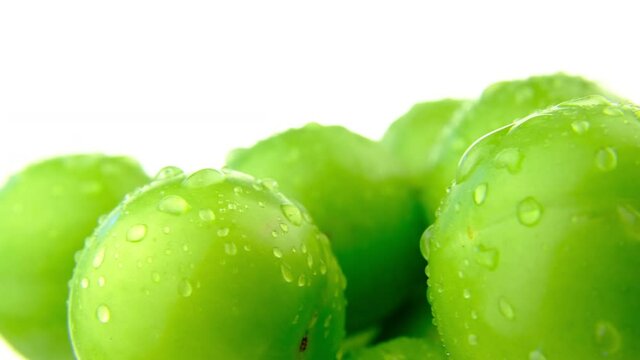 Plums rotating on white background. Fresh organic macro green plum fruit turning real shot 4K closeup background video  water drop.