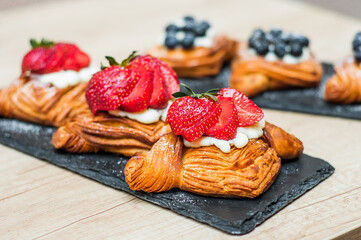 Delicious puff pastries with berries and sugar powder on wooden background