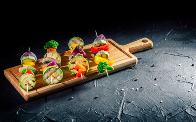 Vegetarian skewers with mixed vegetables (peppers, mushrooms, and onions) on a dark background