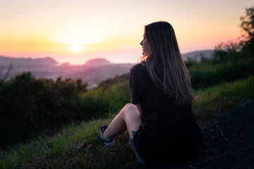 Young girl looking at the sunset from a hill in Donostia-San Sebastian, Basque Country.