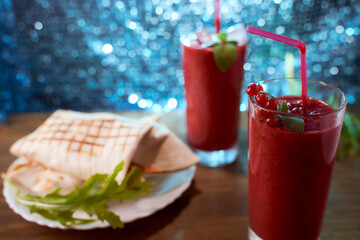 Strawberry and banana smoothies with home made pitas. Long glasses. Blue blurred background