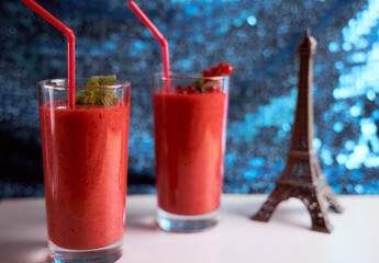 Strawberry and banana smoothies with long glasses on white plate. Blue background