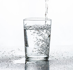 Water being poured into a glass. White background.