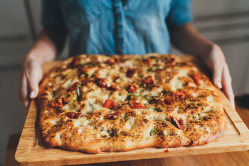 Italian food, Woman holding homemade focaccia with Italian seasoning thyme, rosemary and sun-dried tomatoes, Homemade Food Concept