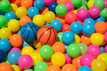 Fototapeta na wymiar Small orange and blue basketballs toy with colorful plastic balls in ball pool