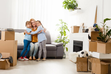 Pretty young mother and her cute little daughter having fun in new apartment and unpacking moving boxes