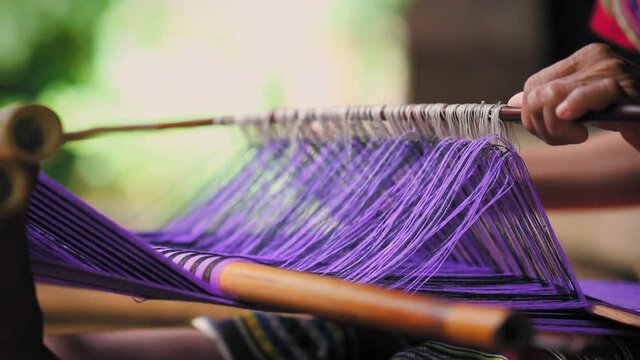 Laos, Pakse. Close up of woman's hand weaving a shawl in a backstrap loom in a village.