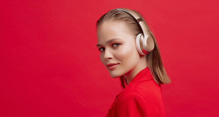 A beautiful young girl in wireless headphones listens to song with a good mood. bright colorful...