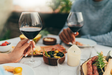Happy couple having romantic date dinner enjoying summer day on rooftop restaurant terrace, Couple in love drinking red wine and eating healthy mediterranean food, People Dinner Food Celebrating