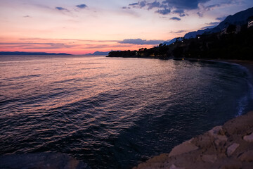 Podgora Chorwacja, zachód słońca nad brzegiem morza, piękne intensywne kolory, wieczorowa pora.