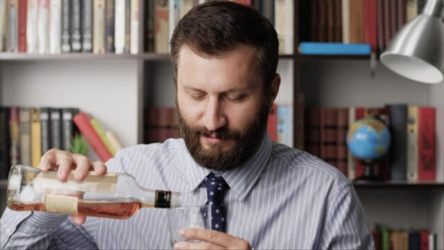 Toast, alcohol addiction, alcoholic, hangover, celebration concept. Handsome bearded smiling man pours into glass alcoholic drink of brandy whiskey scotch bourbon, looking at camera toast. Close-up