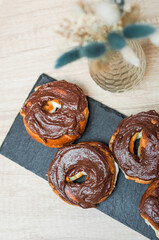 Coffee with a drawn heart and milk on a wooden table in a coffee shop. Chocolate donut with scattering on the table next to the coffee.