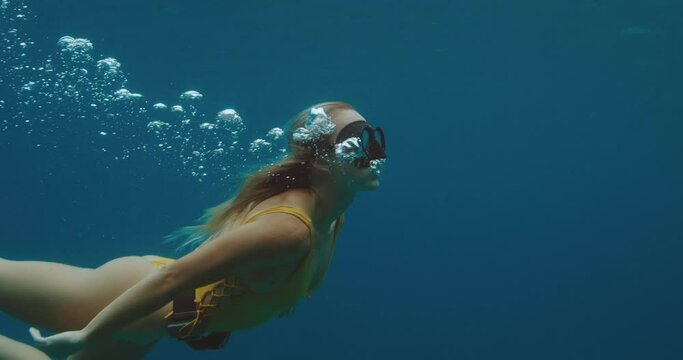 Beautiful sexy woman swimming underwater free diving, outdoor adventure lifestyle, slow motion