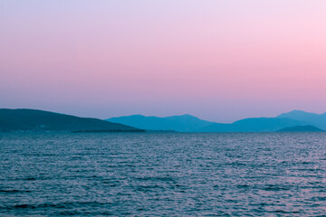 Surreal evening red pink sea landscape, mountains on the background