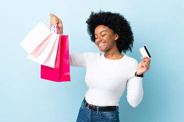 Young African American woman isolated on blue background holding shopping bags and a credit card