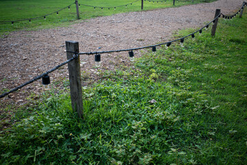 Gravel walking path in a grass field/lawn with light bulb fence