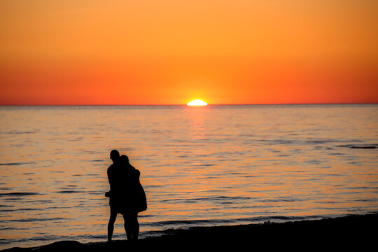 silhouettes of a hugging couple in love on a red sea sunset. Strong feelings. Romantic day.