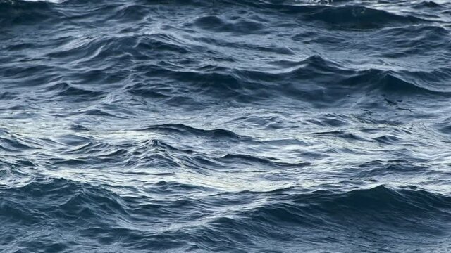 Sea waving during light storm. Day light reflecting on water surface. Blue waves rolling. Slow motion shot