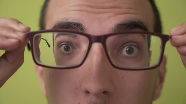 Young man putting on and taking off glasses, concept of myopia and vision problems
